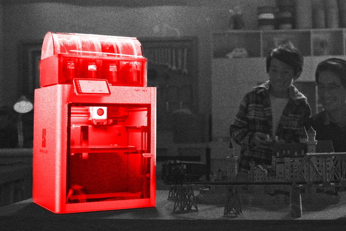 Red-highlighted 3D printer in a grayscale workshop where a parent and child admire miniature models