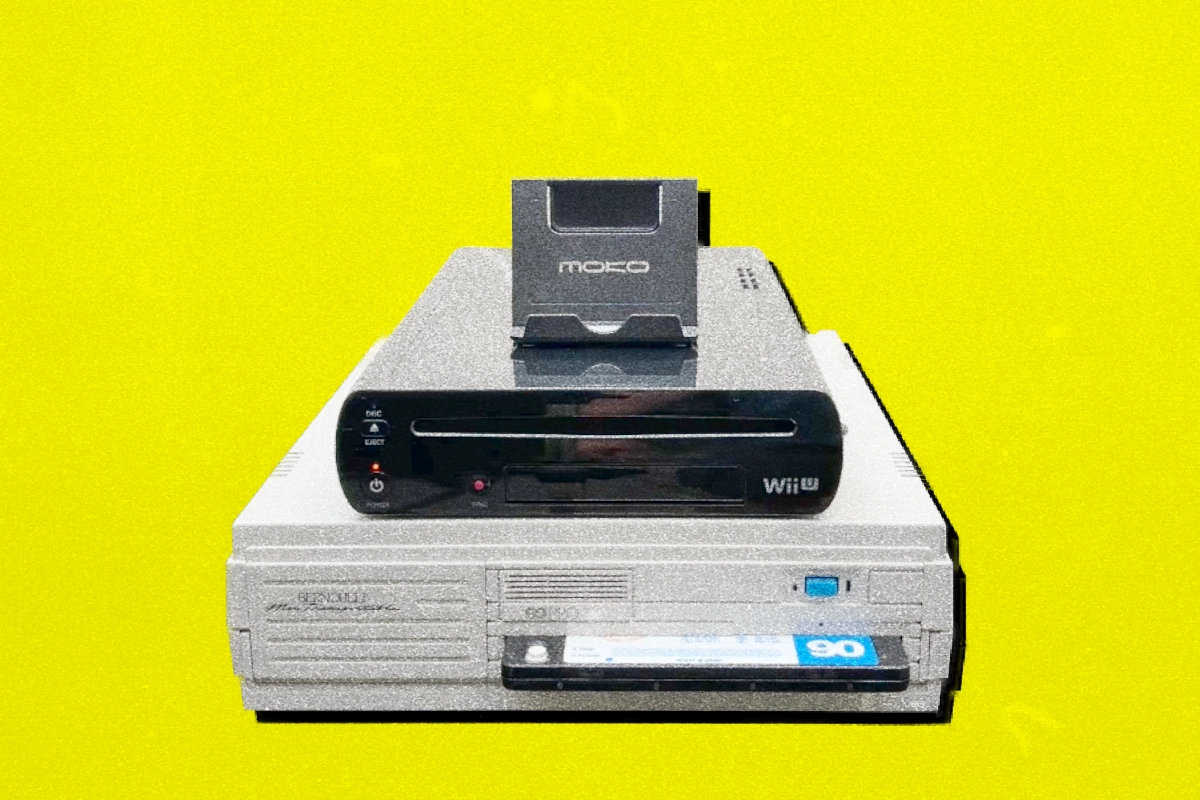 Black Wii U console stacked on a beige Bernoulli disk drive against a yellow background