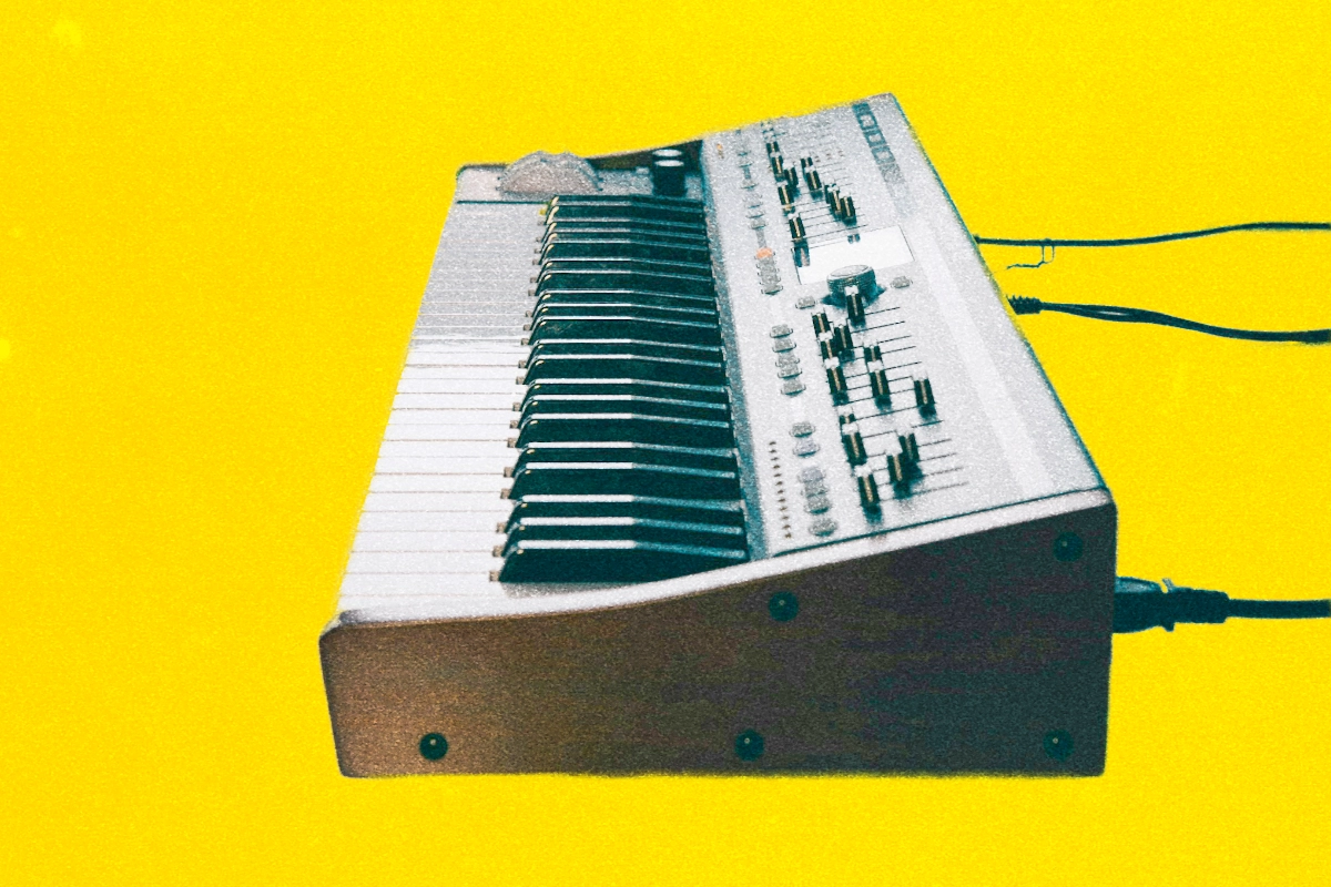 Vintage keyboard instrument with rows of sliders seen end-on against a bright yellow background