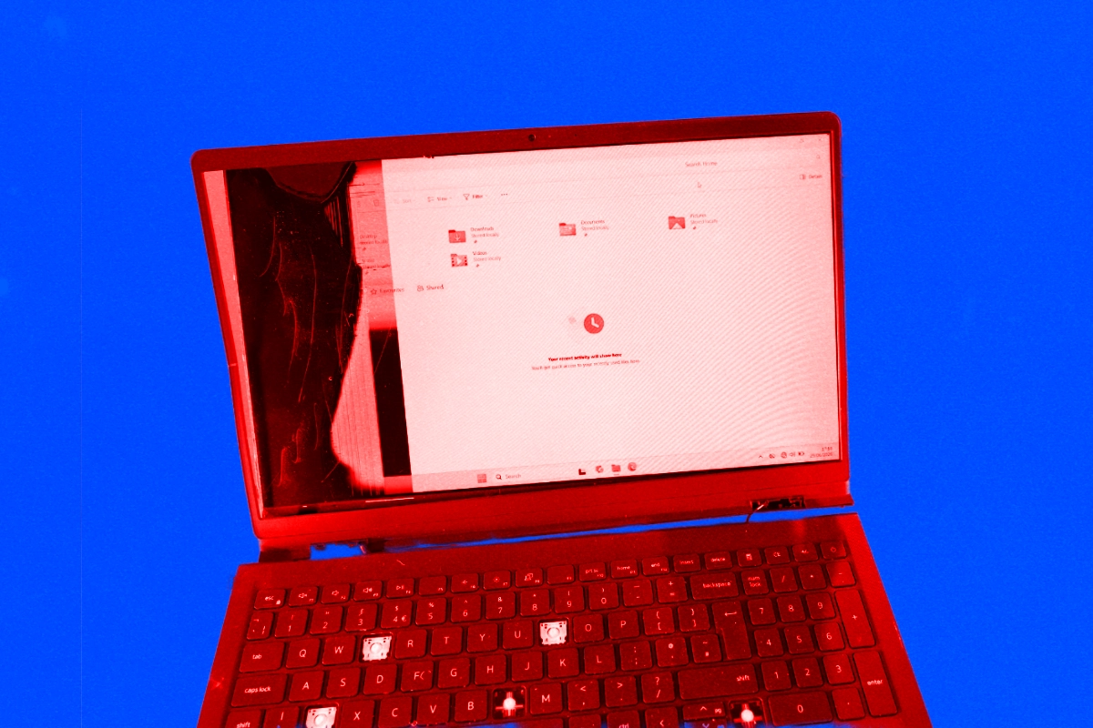 Matt of DIY Perks holding up a red-tinted salvaged laptop motherboard, with more boards laid out on the desk