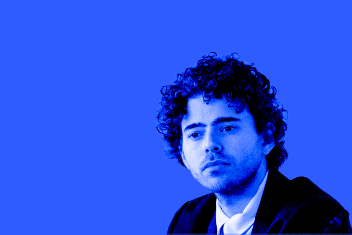 Blue duotone portrait of a young man with curly hair wearing a suit and open collar