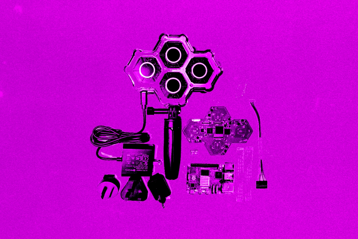 Magenta-tinted flat lay of a hexagonal four-sensor camera rig with cables, plug adapters and circuit boards