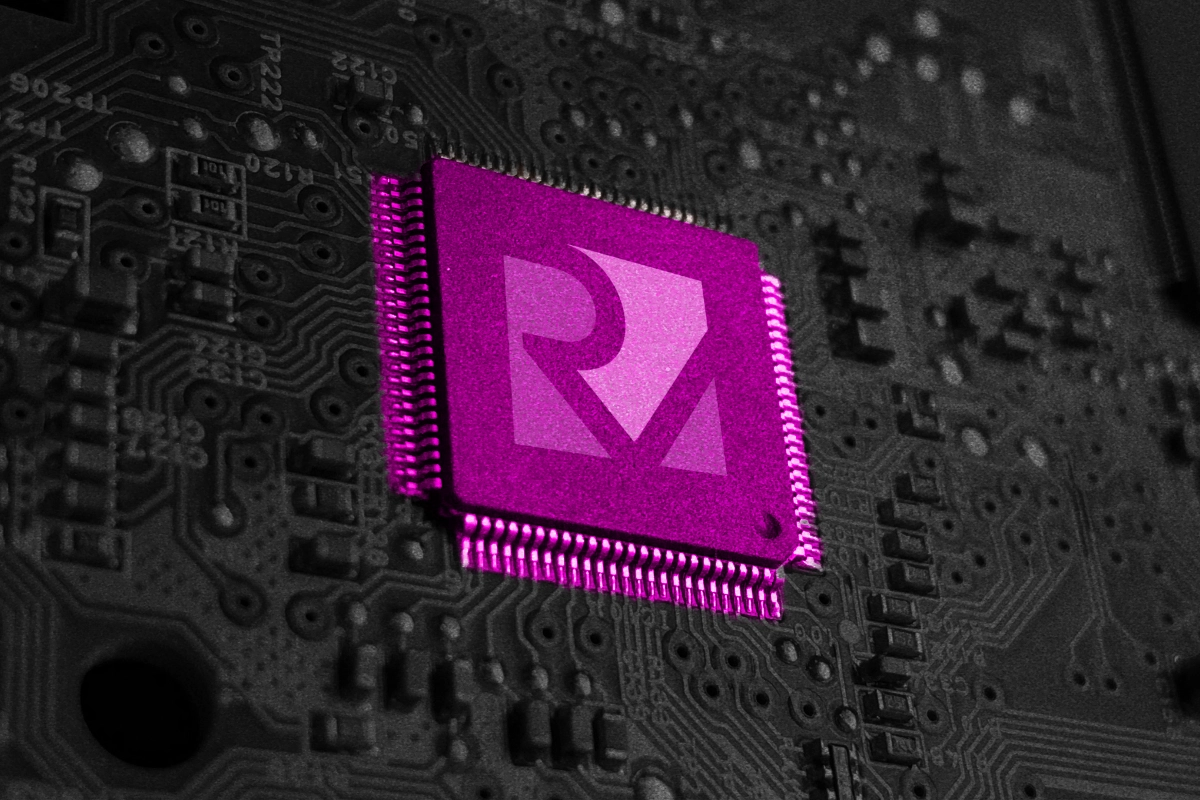 Magenta microchip with the RISC-V logo mounted on a dark gray circuit board