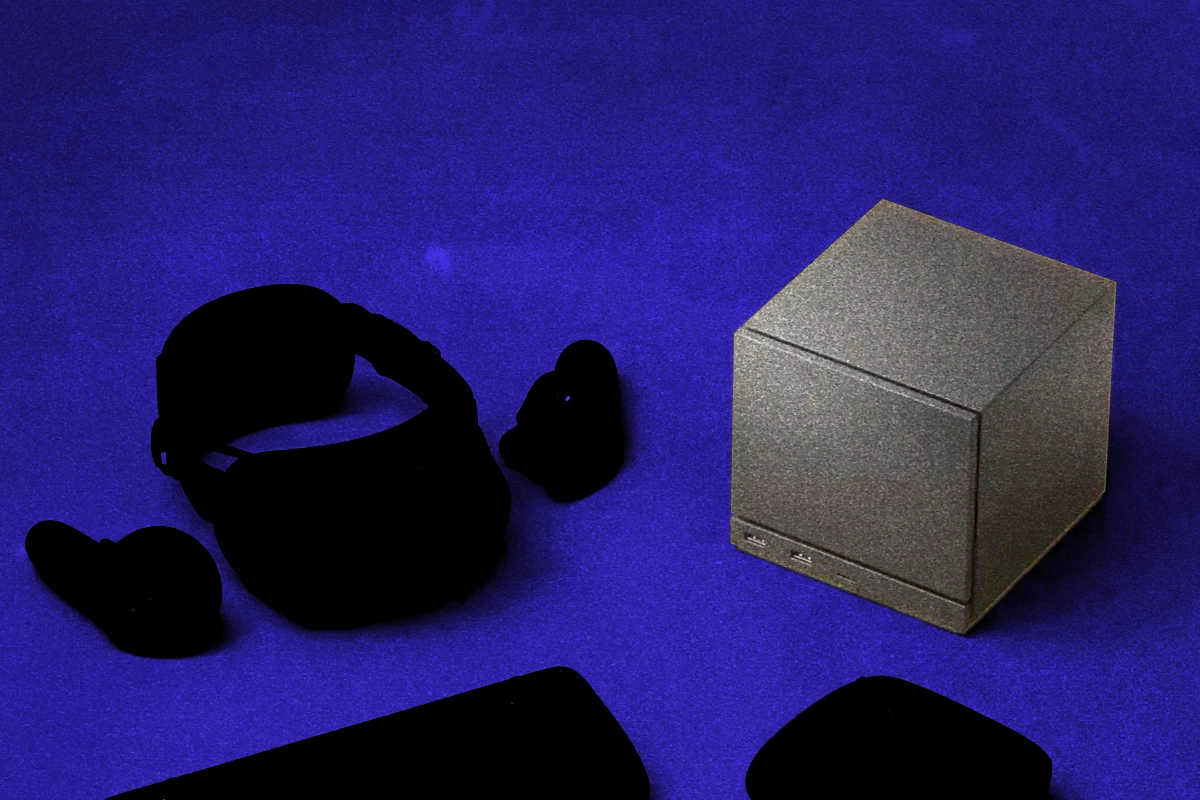 Metallic cube-shaped console beside silhouetted VR headset and controllers on a blue background