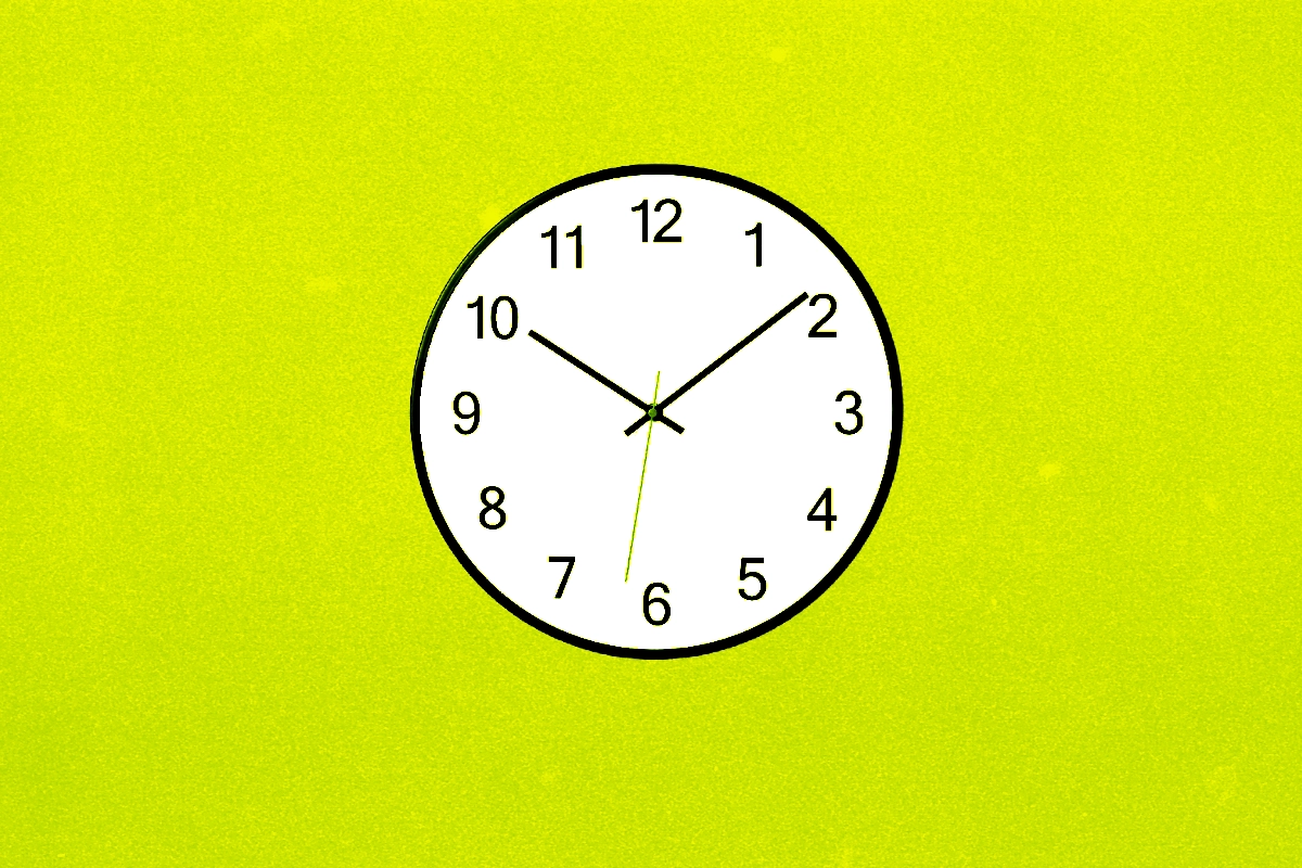 Analog wall clock reading about ten past ten on a bright chartreuse background